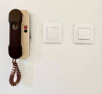 A wall with two switches and an intercom in a studio apartment.