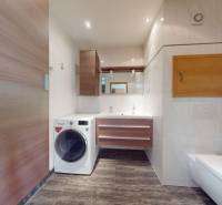 A bathroom with a mirror, a washing machine, and a floor with a wooden decor in a 4-room apartment.