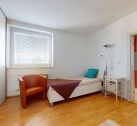Bedroom in a 4-room apartment with a single bed, an armchair, and a wooden decor floor.