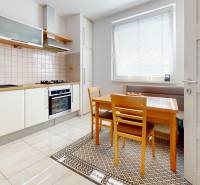 A kitchen in a 4-room apartment with a dining table and white cabinets.