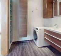 Bathroom in a 4-room apartment with cabinets, a washing machine, and a sink with a dark floor.