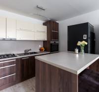 A kitchen in a 2-room apartment with a wooden decor floor, a bar counter, and modern equipment.