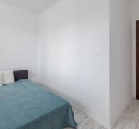 Bedroom in a 2-room apartment with a bed, pillows, and wooden doors.