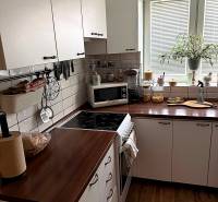 A kitchen in a 2-room apartment with white cabinets and a wood-patterned floor.