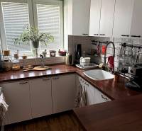The kitchen of a two-room apartment with a wooden decor floor and white cabinets.