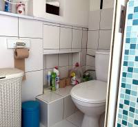 Bathroom in a 2-room apartment with white tiles, storage spaces, and a toilet.