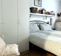 A bedroom in a 2-room apartment with a bed, a wardrobe, and a floor with a wooden decor.