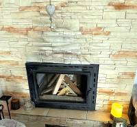 Fireplace in a 2-room apartment with artificial stone cladding and a decorative heart.