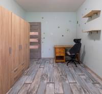A room in a 4-room apartment with a wooden decor floor, a desk, and a wardrobe.