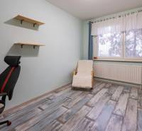 A room with a chair, shelves, and a floor with a wood decor in a 4-room apartment.