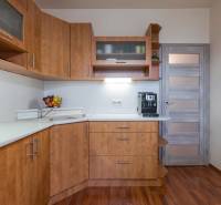 A kitchen with cabinets and a wooden decor floor in a 4-room apartment.