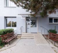Entrance to the building on Vyšehradská Street in Bratislava - Petržalka with benches and greenery.
