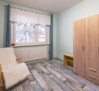 A room in a 4-room apartment with a wardrobe, an armchair, and a floor with a wooden decor.
