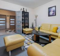 Living room of a 4-room apartment with a yellow leather sofa, glass display cabinet, and a painting on the wall.