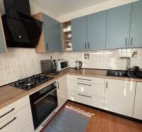 A kitchen in a 3-room apartment with tiled walls and a floor with a wooden design.