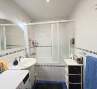 Bathroom in a 3-room apartment with a bathtub, shower, and washing machine, tiles with decor.