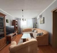 Living room with a comfortable sofa, wooden decor flooring, and pleasant lighting in a 3-room apartment.