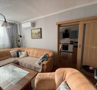 Living room with a sofa, glass table, and kitchen in a three-room apartment.
