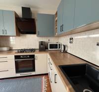 A kitchen unit in a 3-room apartment with a wooden decor floor and appliances.