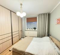 Bedroom with a bed, built-in wardrobe, and wooden decor flooring in a 3-room apartment.