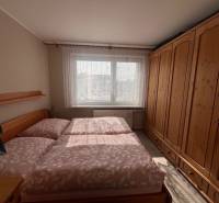 A bedroom in a 3-room apartment with a large wooden wardrobe and a bed.