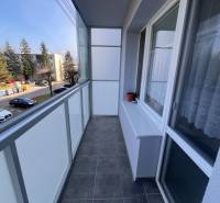The balcony of a 3-room apartment in Rajec with dark tiles and a view of a well-maintained street.
