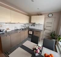 A kitchen in a 3-room apartment with light cabinets and a dining table.
