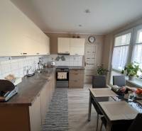 A kitchen in a 3-room apartment with a table, appliances, and plants.