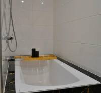 Bathroom in a 3-room apartment with a bathtub, showerhead, and white tiles.