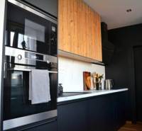 A kitchen in a 3-room apartment with black cabinets and a built-in oven, floor with wood decor.