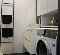 Bathroom in a 3-room apartment with a washing machine, ladder towel rack, and white walls.