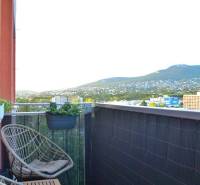 A balcony with rattan chairs and a view of greenery in a 3-room apartment.