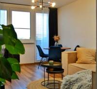 Living room with wood-patterned flooring, a comfortable sofa, and a shaggy blanket in a three-room apartment.