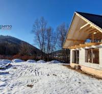 A winter construction of a cottage by the street in Mýto pod Ďumbierom in a snowy landscape.