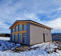 A cottage on a snowy street in Dolná Lehota with a view of the forests and mountains.