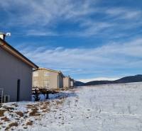 A cottage in a snowy field with a view of the mountains in Dolná Lehota.