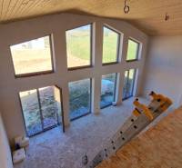 The interior of the cabin with large windows, steps, and a floor with a wooden decor.