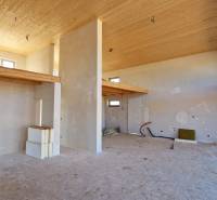 The interior of the cabin with a high ceiling, roughly finished walls, and delicate wooden decorations.