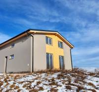 A cottage in Dolná Lehota with wooden decor, a snowy plot, and a cloudy sky.