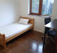 A simple room with a bed, a table, and a wooden floor decor in a 3-room apartment.