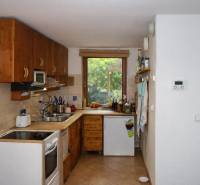 A kitchen in a 3-room apartment with wooden decor cabinets and a window overlooking the garden.