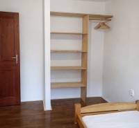 A bedroom with wooden decor, a built-in wardrobe, and a bed in a three-room apartment.