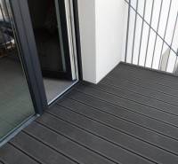 A balcony with a wooden floor on Bodona Street, part of a studio apartment with a large window.