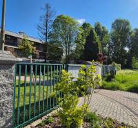 The garden by the building with a brick fence on Bodona Street, near the studio apartment, trees in the back.