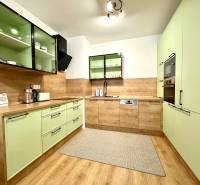 A kitchen in a 2-room apartment with pastel cabinets and a wooden decor floor.