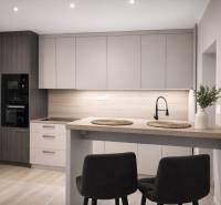 A kitchen in a 2-room apartment with a wooden decor floor, a modern kitchen unit, and a dining table.