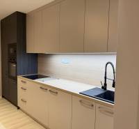 A kitchen unit in a 2-room apartment with a wooden decor floor and built-in appliances.