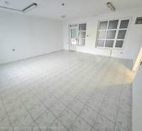 White interior of commercial spaces with tiled flooring and large windows.