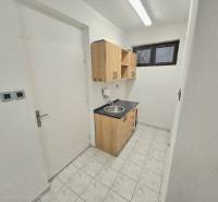 Kitchen corner with a sink and cabinets in commercial premises, tiled floor.