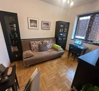 Living room with a sofa and a desk in a family house with wood-patterned flooring.